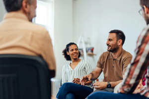 Man laughs while talking to peers in alumni program