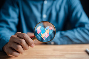 Man looks at puzzle with magnifying class, representing autism spectrum disorder program