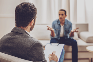 Man sits on couch and expresses himself to doctor during dual diagnosis program