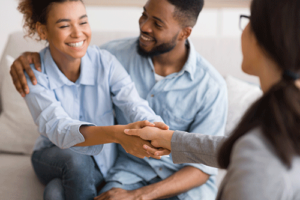 Therapist shakes hand with woman as she and her partner enter family therapy program
