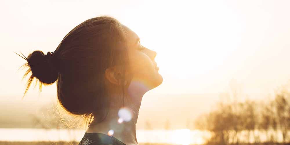 a woman raises her head to the sun after deciding to attend social anxiety disorder treatment